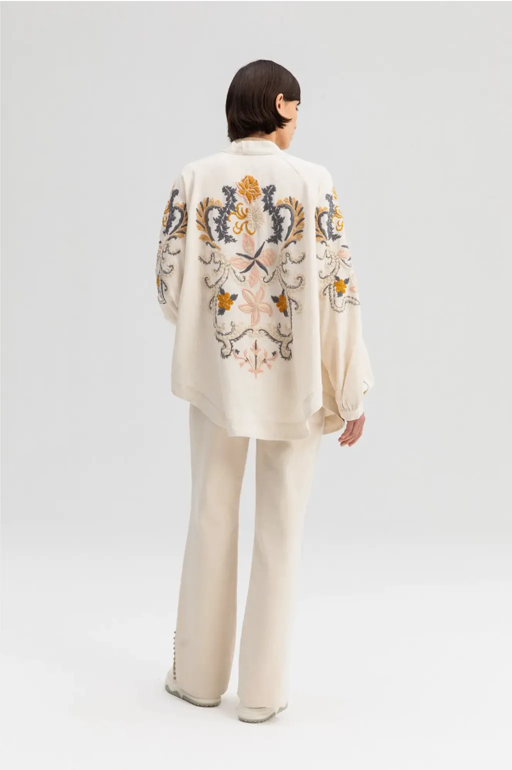 Off-white kimono jacket with embroidery in dusty pastel colors.