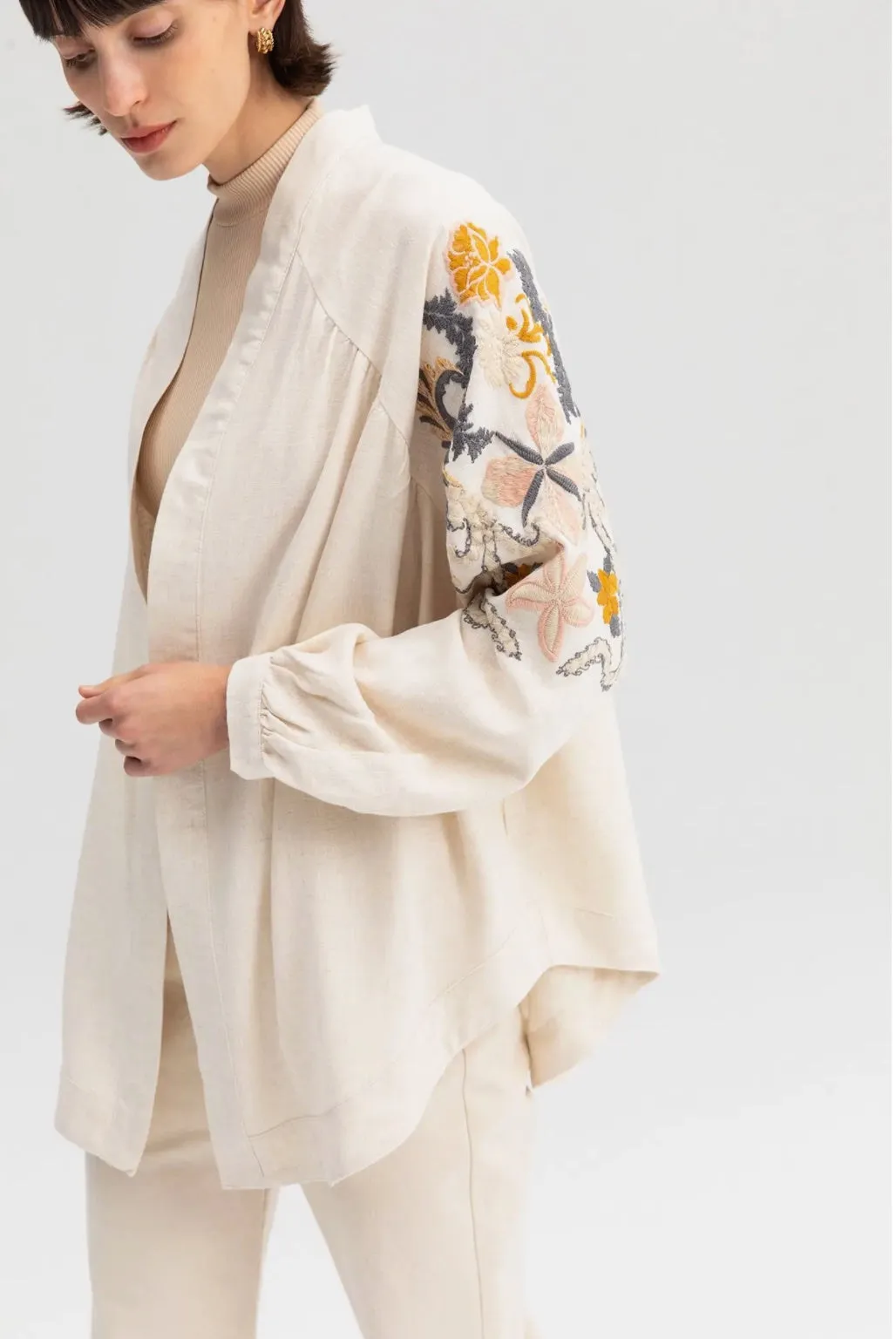 Off-white kimono jacket with embroidery in dusty pastel colors.